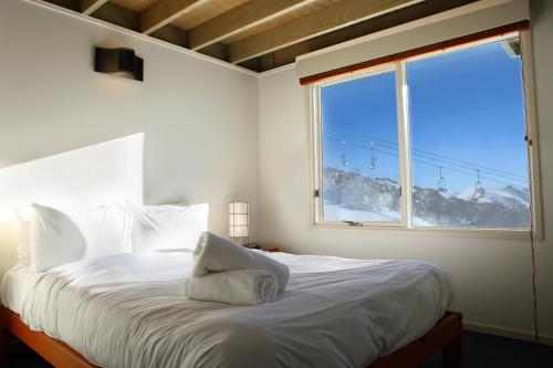 a bedroom with a white bed with a large window at Gotcha in Mount Hotham