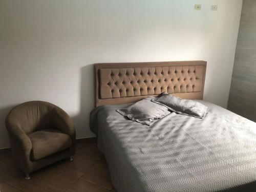 un dormitorio con una cama y una silla en Casa descanso Caraguá 1, en Caraguatatuba