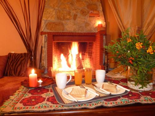 a table with food and candles in front of a fireplace at Theasis suites-Ορεινή Φιλοξενία in Kato Trikala Korinthias