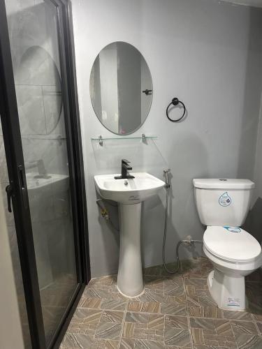 a bathroom with a toilet and a sink and a mirror at Trail Bedz Homestay in Baguio