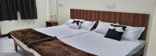 ein Schlafzimmer mit einem großen Bett mit weißen Laken und Kissen in der Unterkunft TARA Guest House in Ujjain