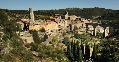 a village on a hill with a bridge and trees at Maison Minervoise in Aigne