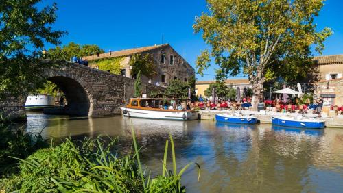 a group of boats in a river with a bridge at Maison Minervoise in Aigne