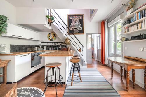 une cuisine avec des placards blancs, une table et des tabourets dans l'établissement Jolie maison Parisienne Jardin Porte de Montreuil, à Bagnolet
