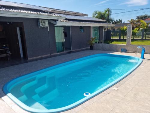 a large blue swimming pool in front of a house at Casa Alto Padrão Perto da Praia C/ Piscina Grande in Guaratuba