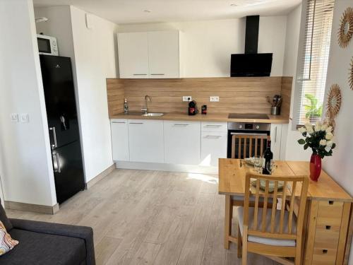 une cuisine avec des armoires blanches et une table en bois dans l'établissement Séjour magique proche aéroport CDG Astérix Disney et Paris Maison toutes commodités, terrasse, WIFI, CLIM, lave vaisselle, à Saint-Mard