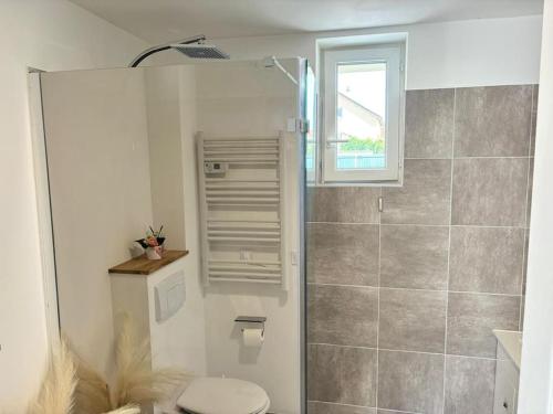 Un baño con inodoro y ducha con ventana. en Séjour magique proche aéroport CDG Astérix Disney et Paris Maison toutes commodités, terrasse, WIFI, CLIM, lave vaisselle, en Saint-Mard