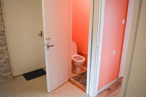a bathroom with a toilet in an orange room at Cherry Apartment in Madliena