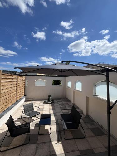 a patio with chairs and an umbrella on a roof at AppartHôtel Elite Spa in Forbach
