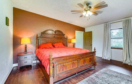a bedroom with a wooden bed with orange pillows and a fan at Spacious Micanopy Farmhouse with Luxurious Pool! in Micanopy
