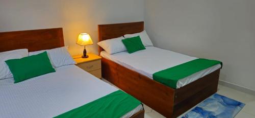 a bedroom with two beds and a lamp on a night stand at Hills Kandy Apartment in Kandy