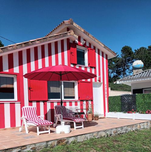 a red and white house with two chairs and an umbrella at Casiña Palmira in Finisterre