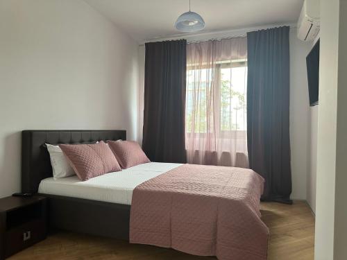 a bedroom with a bed with pink pillows and a window at Happy Pipera 3 Luxury Rooms in Voluntari