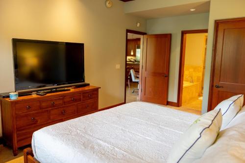 a bedroom with a bed and a flat screen tv at Hilton Pool Pass Included, Kolea - Stylish & Comfy Walk to Beach Patio Pool Gym in Waikoloa