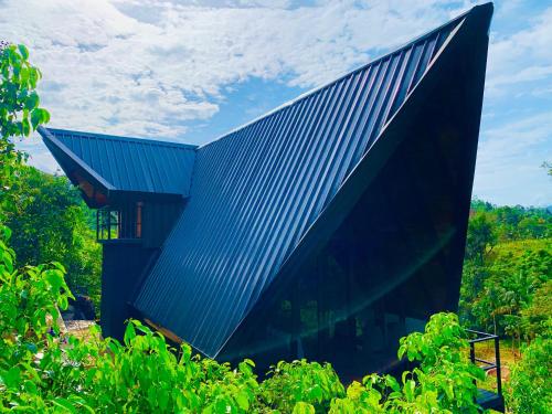 a building with a blue roof on top of trees at Cannelle Hill Cabanas in Deniyaya