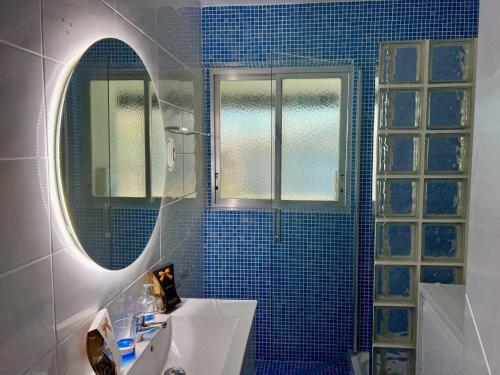 a blue tiled bathroom with a sink and a mirror at Altea Sound of the Sea in Altea