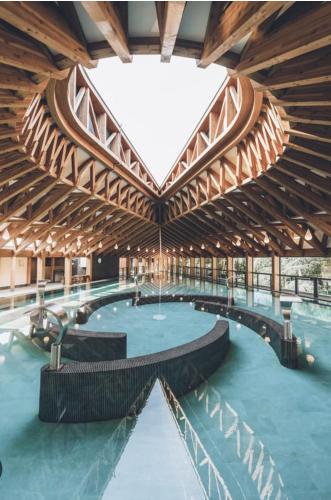 un grand bâtiment avec une piscine et un plafond en bois dans l'établissement Villa Kéana avec Piscine en Sud Ardèche, à Lachapelle-sous-Aubenas