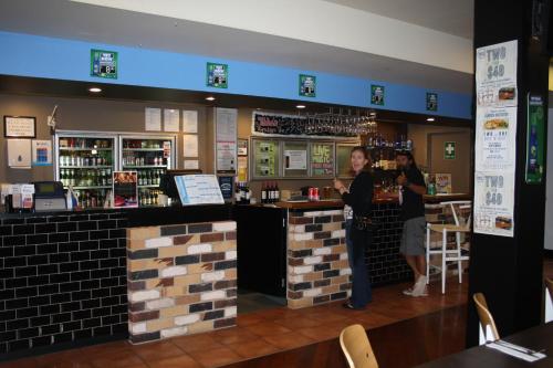 two people standing at a bar in a restaurant at Hotel Beach House Nambour in Nambour