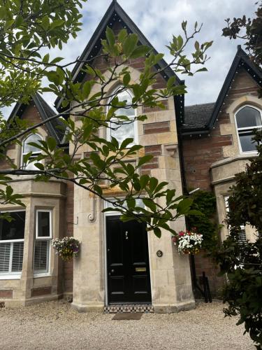 a house with a black door on the side of it at Beinn Mhor Lodge, 63 Culduthel Road in Inverness