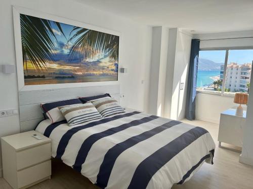 a bedroom with a striped bed and a large window at Altea Sound of the Sea in Altea