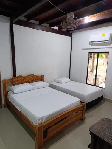 two beds in a room with a window at Hostal Brisa y Mar in Arboletes