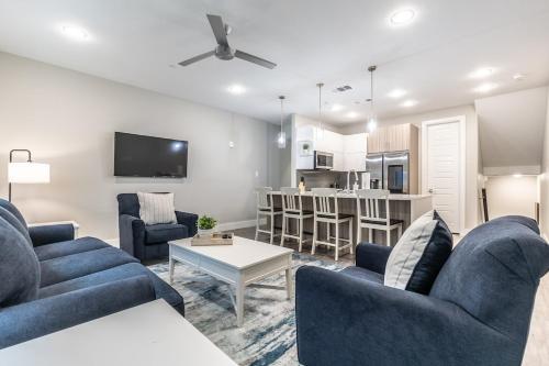 a living room with two blue couches and a kitchen at Magnolia District Modernism in Fort Worth