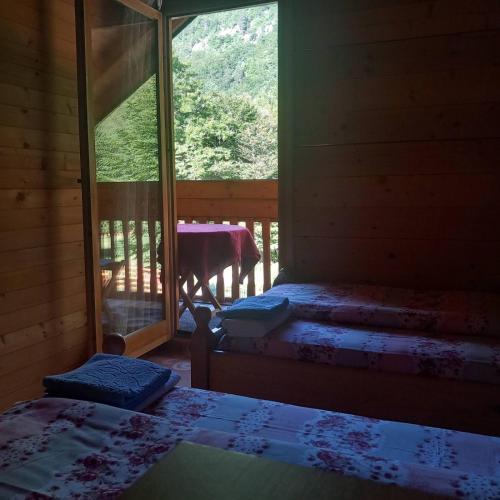 a room with two beds and a balcony with a table at Prokletije Vucetic sobe in Dolja