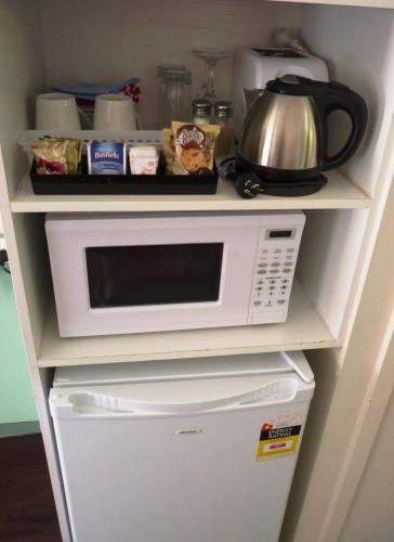 a white microwave sitting on top of a refrigerator at Winchester Motel in Moree