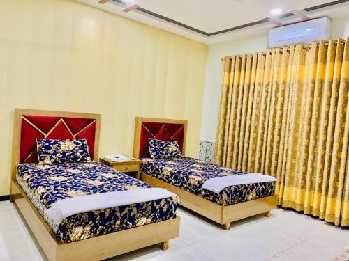 two beds in a room with yellow walls and curtains at Guest House near islamabad airport in Islamabad