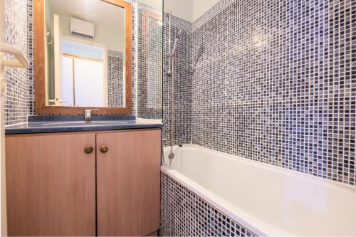 une salle de bain avec un lavabo, une baignoire et un miroir dans l'établissement Résidence le Hameau de Cap Esterel - maeva Home - Appartement 2 pièces 5 personnes - Sélection MAE-1281, à Saint-Raphaël