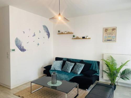 un salon avec un canapé noir et une table dans l'établissement Confort appart entre Paris & Aéroport Charles de Gaulle, à Goussainville