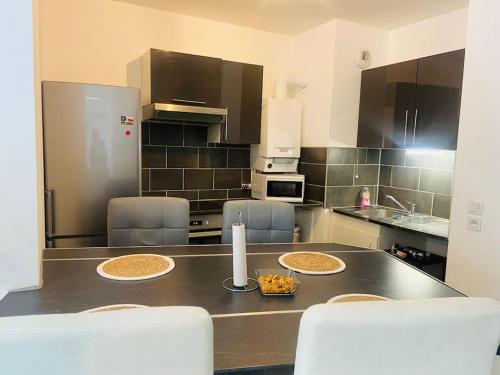 a kitchen with a counter top with chairs and a refrigerator at Confort appart entre Paris & Aéroport Charles de Gaulle in Goussainville