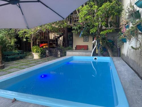 a blue swimming pool with an umbrella at Hospedagem Praia de Piratininga in Niterói