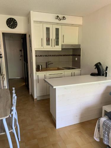une cuisine avec des placards blancs et une horloge murale dans l'établissement Joli studio alcôve proche Port Malfato piscine au Cap d'Agde, au Cap d'Agde