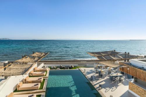 a resort with a pool and chairs and the ocean at NOIMA Casa Unico in Megalochori