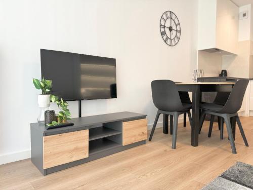 a living room with a dining table and a flat screen tv at Apartamenty Florina Q4Apartments in Łeba