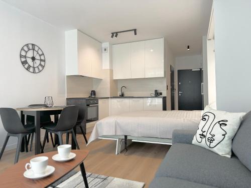 a bedroom with a bed and a table and a kitchen at Apartamenty Florina Q4Apartments in Łeba