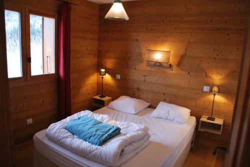 une chambre avec un lit dans un mur en bois dans l'établissement Le Petit Réconfort, accès skis aux pieds, à Saint-François-Longchamp