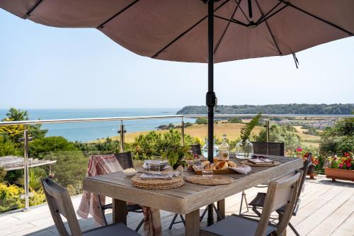 a wooden table with an umbrella on a deck at The Spinney - Spectacular views over the bay and close to beach with parking in Paignton