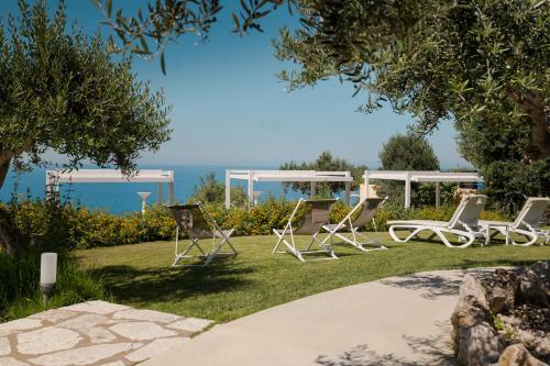a group of lawn chairs sitting in the grass at Hotel La Tavernetta in Scopello