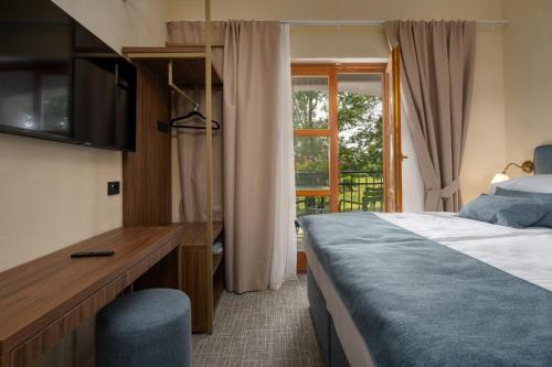Un dormitorio con una cama y un escritorio y una ventana. en Boutique Hotel Paradiso, en Poreč