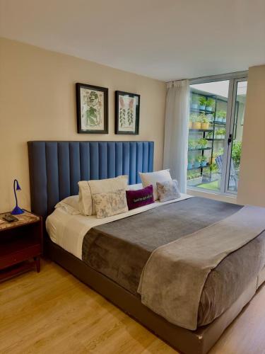 a large bed with a blue headboard in a bedroom at Hotel Living 55 in Bogotá