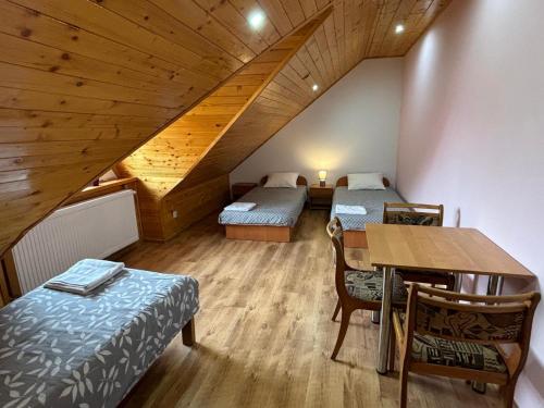 a room with two beds and a table in a attic at Agroturystyka u Darka in Kolno