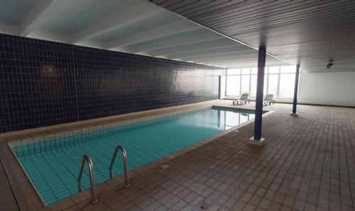 ein großer Swimmingpool in einem Gebäude mit Fliesenboden in der Unterkunft Studio plein centre, calme, parking inclus, piscine et gardien in Grenoble