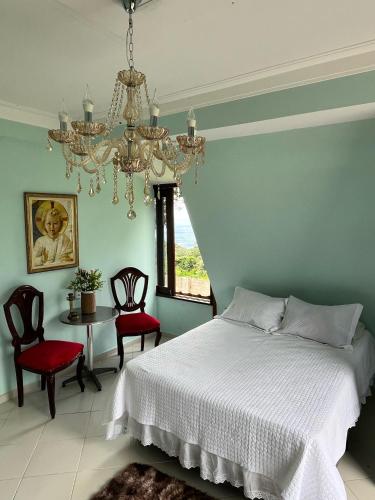 a bedroom with a bed and chairs and a chandelier at Chalé Suíça da Serra in São Benedito