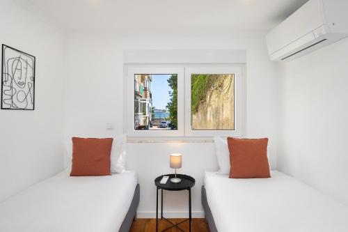 two beds in a white room with a window at WHome Peaceful Algés Family Home away from City Noise in Algés