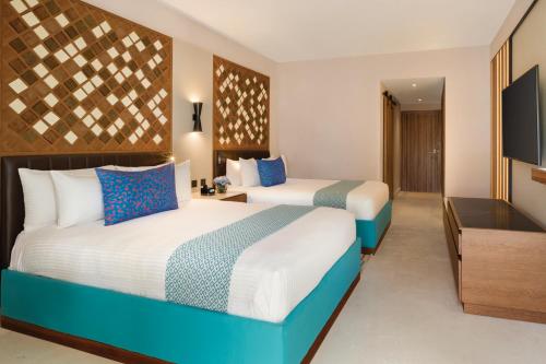 a hotel room with two beds and a television at Secrets La Romana All-Inclusive Adult Only Resort & Spa in Bayahibe