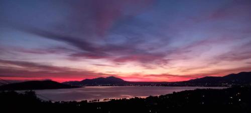 a sunset over a body of water with mountains at Villa Aelia Luxury Maisonette in Salamís