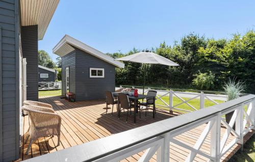a wooden deck with a table and an umbrella at 2 Bedroom Nice Home In Gudhjem in Rø