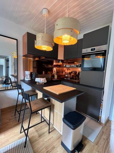 une cuisine avec des armoires noires, une table et des chaises dans l'établissement Cozy Pyrenees Mountain Retreat, à Castillon-de-Larboust